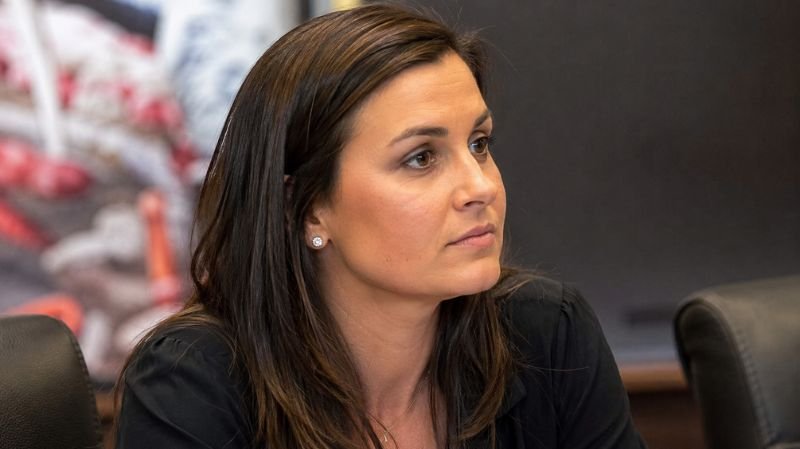 Ultra-realistic portrait of Jessica Dorrell sitting in a professional office setting during her early career in Arkansas athletics.
