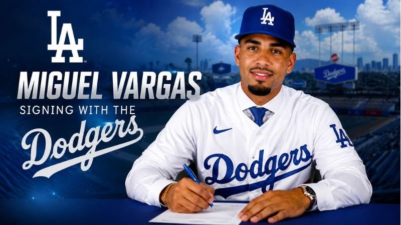 Miguel Vargas wearing a Los Angeles Dodgers uniform while signing his contract at a table with Dodger Stadium in the background.